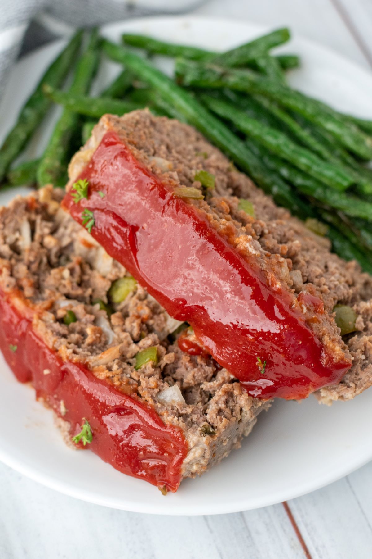 meatloaf on white plate with green beans