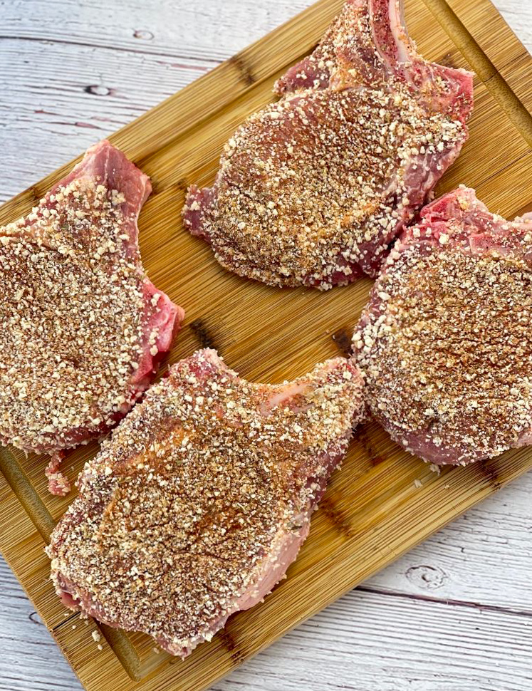 seasoned pork chops on cutting board