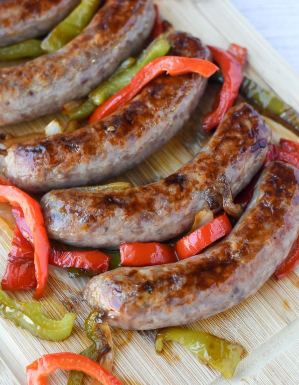 brats with peppers on cutting board