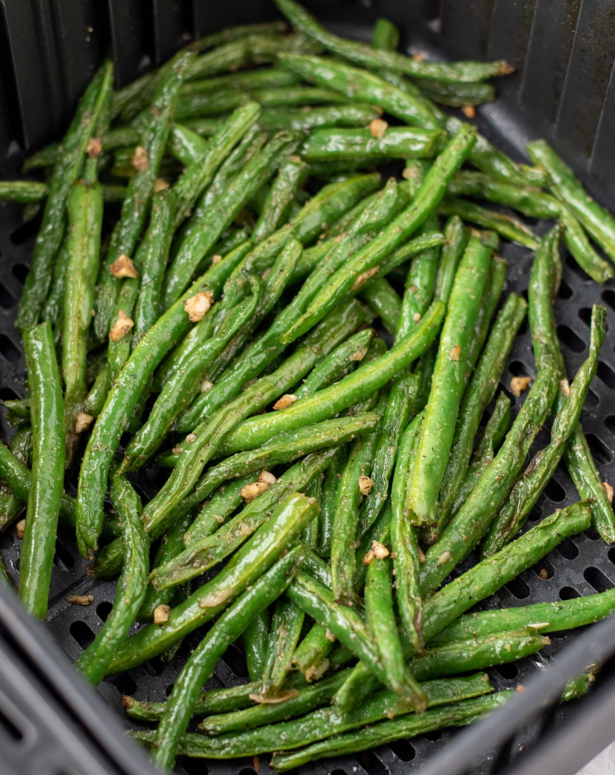 cooked green beans in air fryer basket.