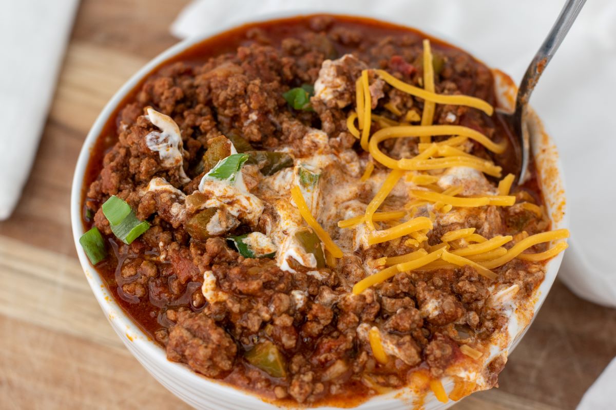 chili mixed with sour cream and cheddar in white bowl